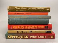 Front stacked view of the seven vintage antiques, dolls, and Royal Doulton figurine reference books showing titles and condition wear