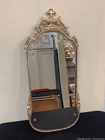Full view of the mirror showing overall size, shape, and decorative frame with a fleur-de-lis finial on top.