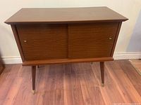 Front view of wooden media console with sliding doors closed.