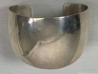 Wide sterling silver cuff bangle showing the polished front curved surface.