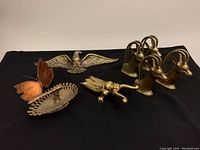 Overview of all lot items on black backdrop including bootjack, bookends, eagle, butterfly and decorative dish
