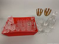 Image showing red tray containing assorted vintage cut crystal glassware including stem glasses of various styles and sizes, and a 9 inch cut crystal decanter.
