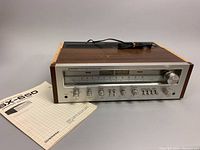 Angled view of receiver with manual positioned on left, power cord coiled on top