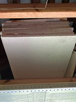 11 sheets of rigid foam insulation stacked upright between wooden rafters in a garage.