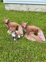 All three fox garden statues placed on grass to show size and condition, two large cement and one smaller plastic.