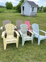 Photo showing set of six plastic Muskoka lawn chairs in various colors on grass, with a small shed in background