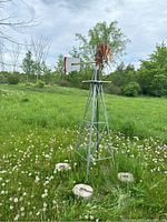 Full view of the 8 foot tall garden windmill standing in grassy field showing rusty blade assembly and lattice metal base.