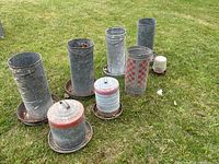 Overview photo of all 8 poultry feeders arranged on grass showing various sizes and designs.
