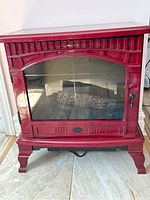 Front view of red Dimplex electric wood stove featuring glass window showing simulated logs inside.