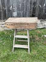 Wooden egg crate box on top of 2ft wooden step ladder outside against wooden fence