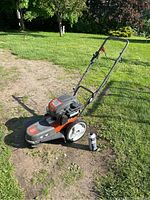 Front angle view of walk-behind trimmer showing handle, wheels and cutting head.