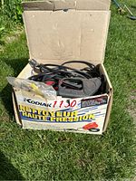 Electric pressure washer with cords and spray gun inside original Kodiak box on grass.