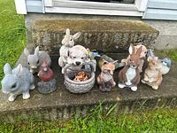Front view of all garden figurines arranged on stone steps, showing bunnies, birds, dog, fox, and decorative basket with leaves.