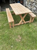 Side view of the wooden picnic bench on grass, showing the table top and attached benches.