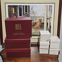 Stack of four red Danbury Mint outer boxes reading 'Gold Christmas Ornament Collection' and two stacks of white ornament boxes (3 pc and 4 pc).