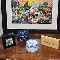All four Disney character watches with their respective boxes displayed together on a wooden table in front of a colorful Disney collage print.
