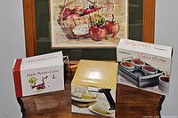 Image showing boxed apple peeler-corer and creme brulee set torch with ramekins, all boxed and arranged on a wooden surface.