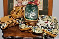 View showing multiple Longaberger baskets including the large rectangular basket with floral liner on the right and a stack of smaller baskets with covers on the left.