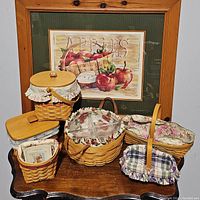 Group of all five Longaberger baskets displayed on tabletop against framed print