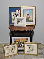 Full grouping of Disney Mickey Mouse and related character framed art pieces arranged around small wood tables.