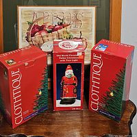 Photo of the three Santa figurines in their boxes, showing Clothtique branding and Old World Christmas box in center.
