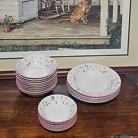 Photo showing stacks of soup, salad, and small bowls with floral Summer Chintz pattern and pink scalloped rims.