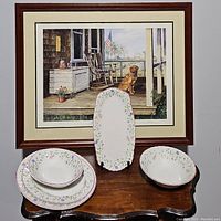 Full set of three platters and two serving bowls in Johnson Brothers Summer Chintz pattern placed on a table with framed dog and porch painting in background.