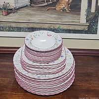 Stacked Summer Chintz plates showing three sizes stacked by size on a wood surface in front of a framed painting.
