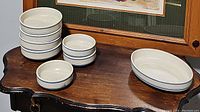 Photo showing all stacked bowls and oval casserole dish on wooden table, displaying blue stripe pattern around rim.
