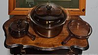 Photo of the full set showing the large round Dutch oven, small saucepan, and skillet pan on a wooden surface.