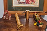 Four wooden kaleidoscopes, three are rectangular and one is smaller with a bead-filled element, shown on wooden surface.