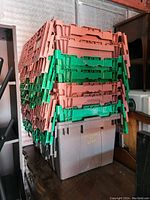 Photo of 8 stackable plastic storage totes in brown, green, and gray, stacked on top of each other.