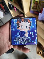 Front view of a small square container showing blue Betty Boop design with signature text.