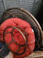 Image shows a dark brown rattan papasan chair frame with matching base and a thick tufted red cushion folded inside the chair frame.