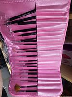 Image of multiple black handled Gelmoment makeup brushes arranged in a pink foldable carrying case with slots for each brush