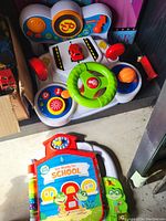 Photo showing two children's toys: a Vtech steering wheel toy with interactive features and a LeapFrog educational toy with a green frog character.