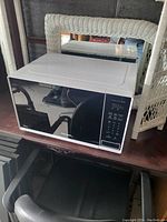 Closed view of white microwave oven with black glass door and digital control panel on right side.