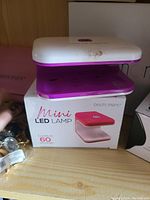 Mini LED lamp in white and pink with box showing brand Geumemere, curing gel in 60 seconds.