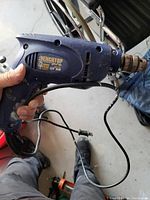 Photo of blue and black corded handheld power drill showing brand label, model, and cord with plug visible