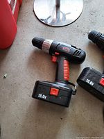 JobMatic 18.0V cordless power drill with red accents and silver metallic chuck ring, placed on a concrete surface.