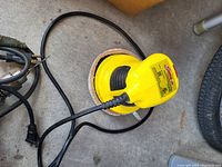 Yellow Shur-Line handheld electric power sander with black accents, power cord, and plug shown resting on the floor.