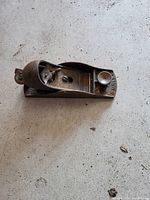 Metal Stanley wood hand plane on concrete floor showing top and side with adjustment knob and blade housing.