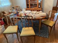 Five wood frame armless chairs with yellow fabric upholstery in sun motif pattern arranged around a table.