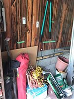Various gardening tools and outdoor items including folded camping chairs, extension cords, planter containers, garden sprayer