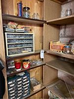 Overview of wooden shelving with two plastic organizer units containing assorted hardware items such as screws, nails, bolts, tacks. Various jars and boxes also visible on shelves.