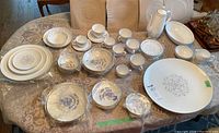 Full view of all dishware, cups, and serving pieces laid out on a table for scale and content overview.