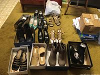 Wide view of assorted women's shoes in boxes and on the floor including boots, heels, and sandals in various colors.