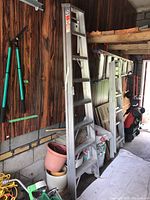Ladder leaned against wall in garage showing full side view and storage context