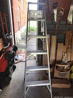 Front view of aluminum step ladder fully extended in garage setting.