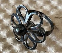 Close-up of the sterling silver flower motif ring showing the open petal design and center round bead, with visible 925H mark.